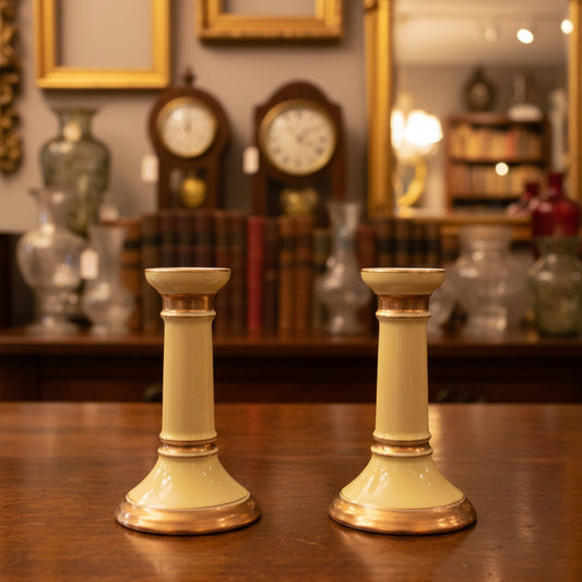 Two gold candle holders on a dark green fabric background
