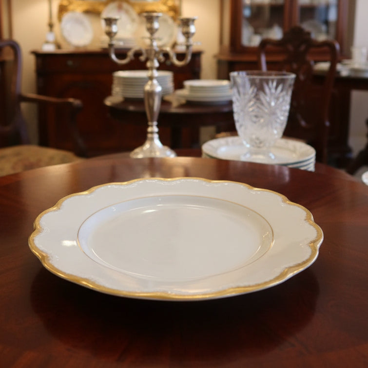 White plate with gold rim on a green fabric background