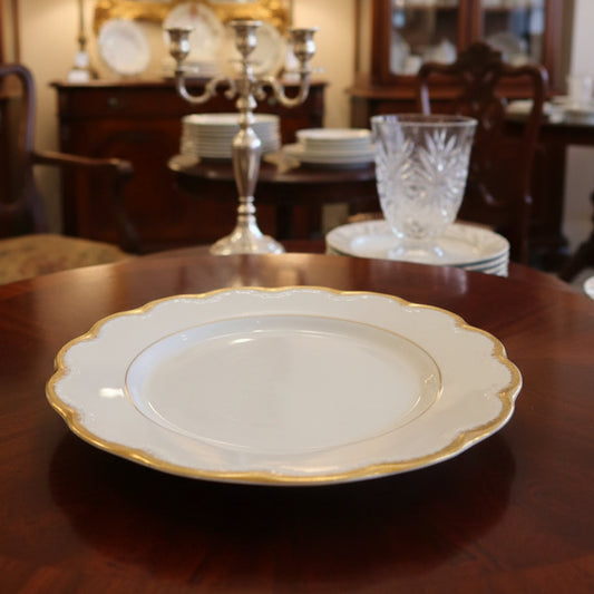 White plate with gold rim on a green fabric background