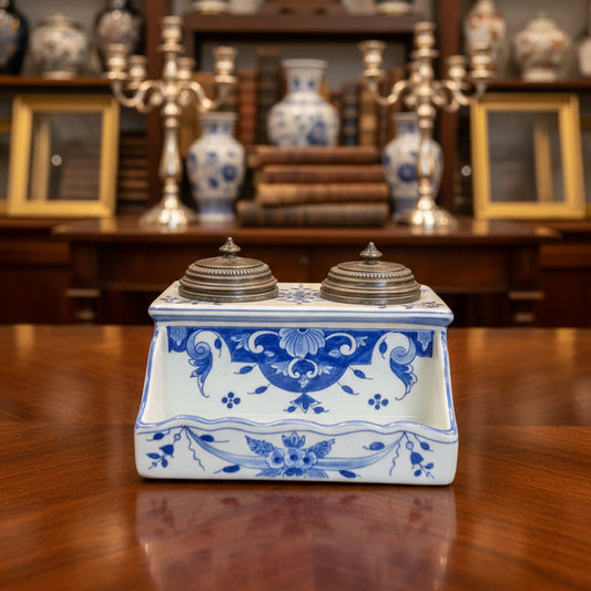 Decorative ceramic inkwell with blue and white design on a green fabric background