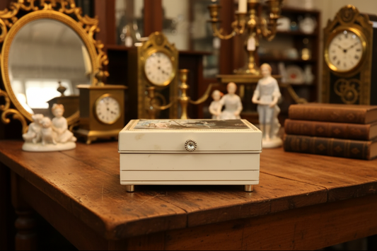 Decorative jewelry box with a painted lid featuring people by a lake on a light-colored surface.