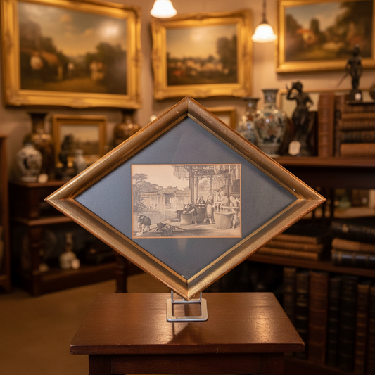 A vintage diamond-shaped framed art piece with a sepia-toned illustration, displayed on a stand against a draped dark green fabric backdrop.
